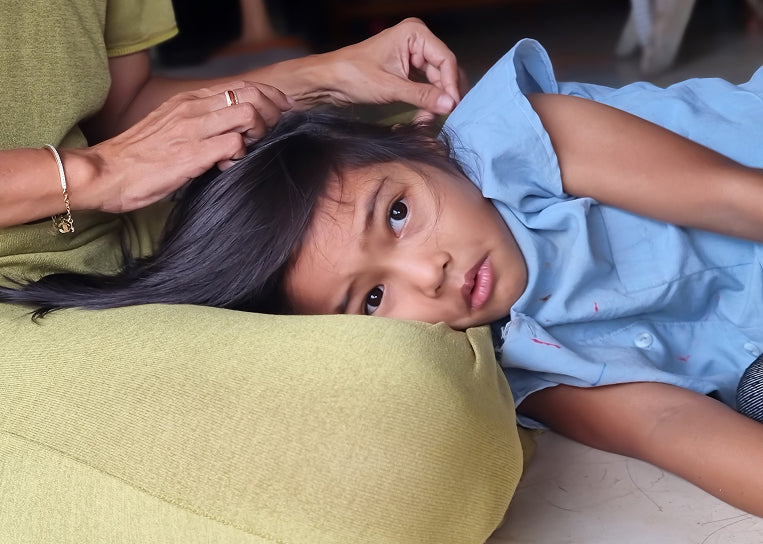 A young girl lying in her mother's lap while the mother strokes her hair.