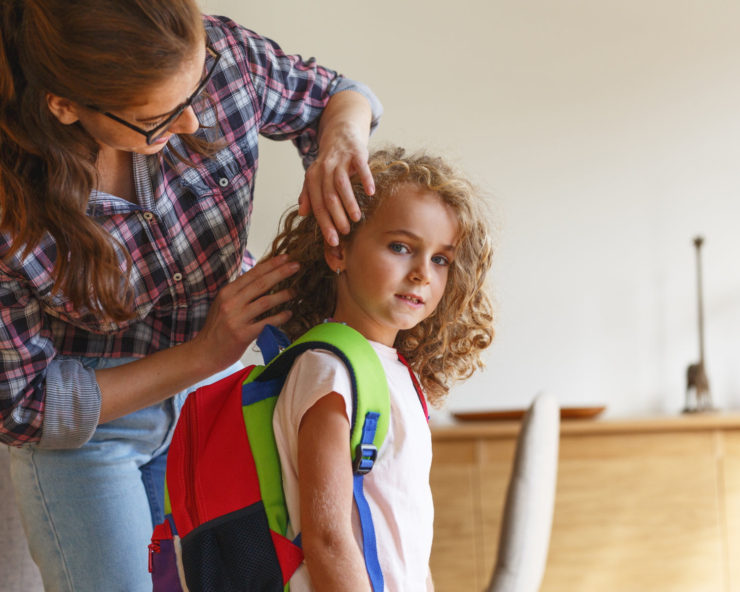 Woman checking child's hair before school