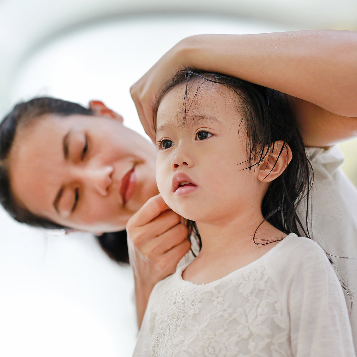A woman checking her daughter's hair for lice.