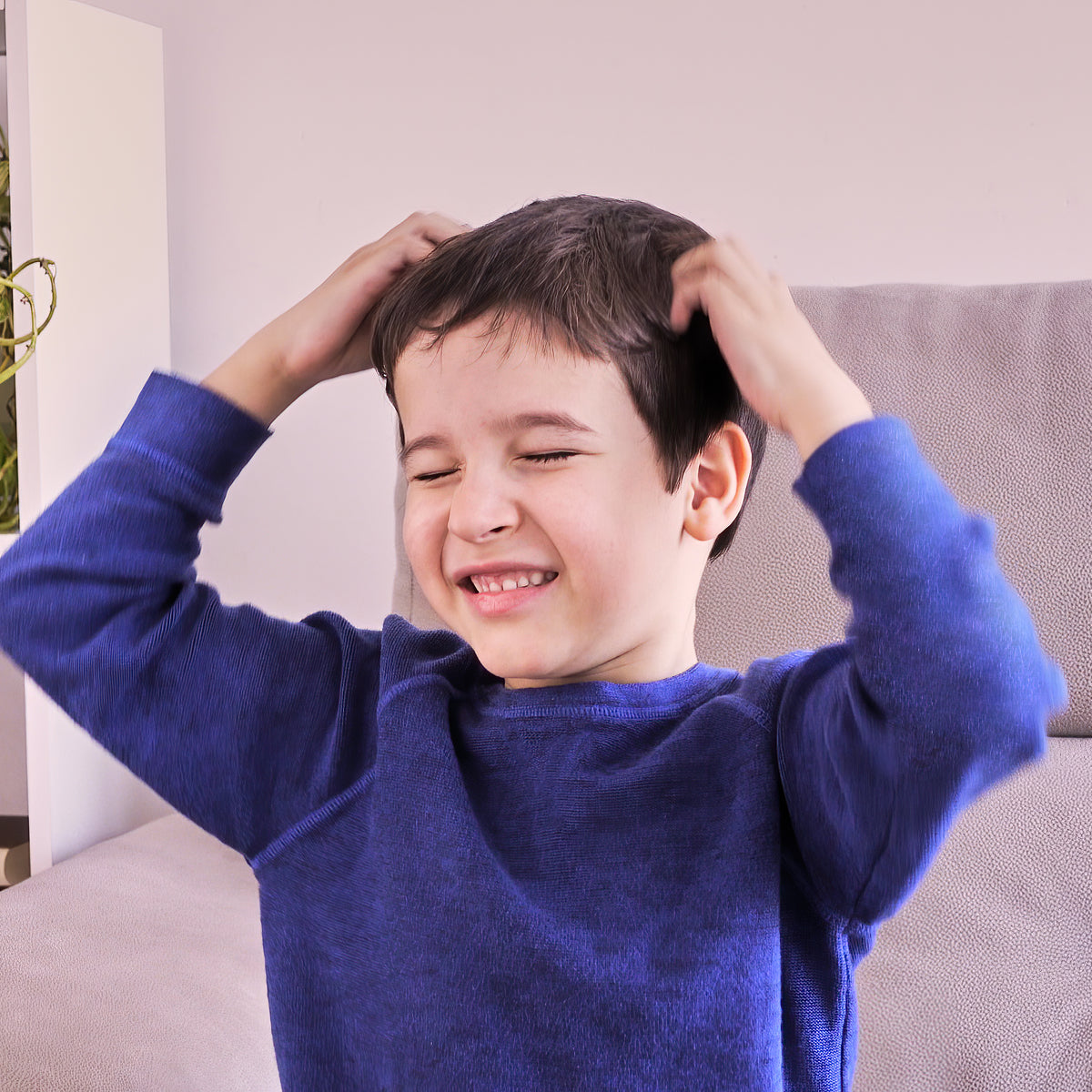 Child wearing a blue sweater itching his head