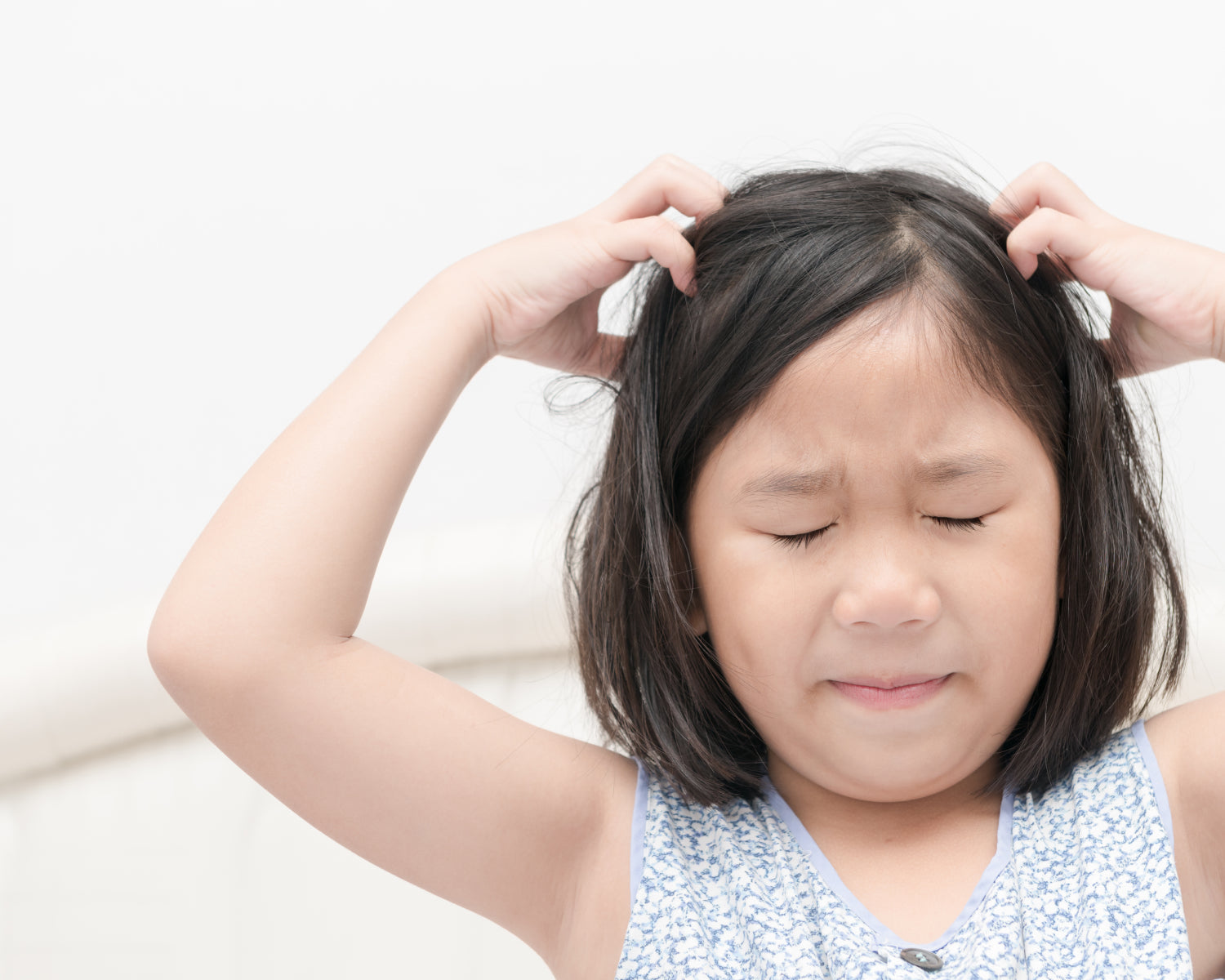Young girl with a pained expression, itching her head.