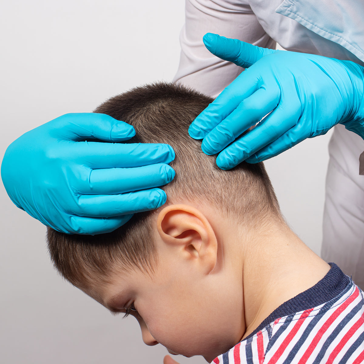 Person with blue gloves examining a child's head